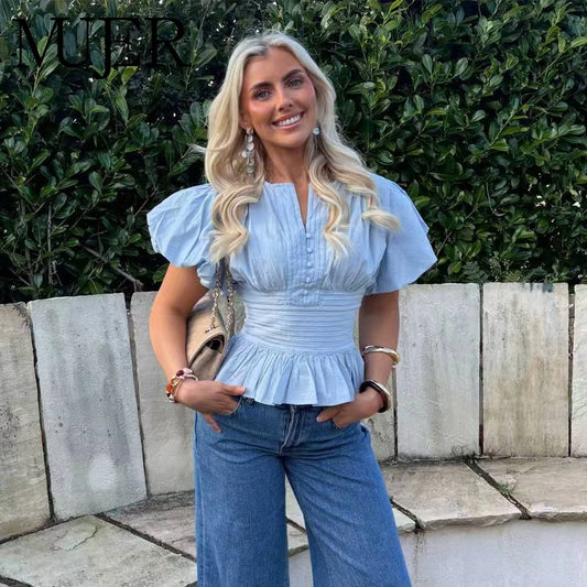 Woman wearing a light blue elegant peplum blouse with puff sleeves outdoors.