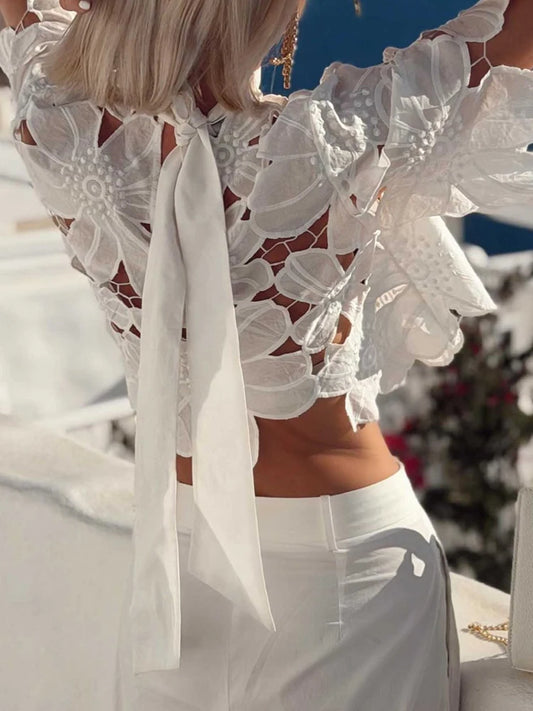 Close-up of a white floral lace cutout blouse with intricate detailing.