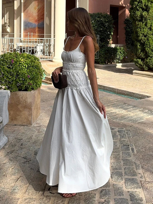 Woman wearing a white elegant smocked maxi dress for a beach vacation.