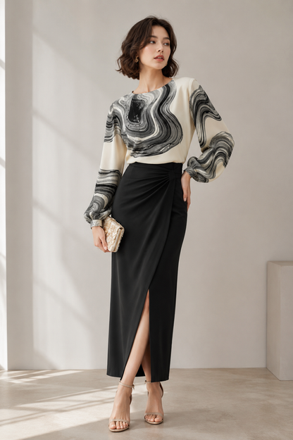 Woman wearing a black and ivory printed chiffon blouse with long sleeves and a round neckline.