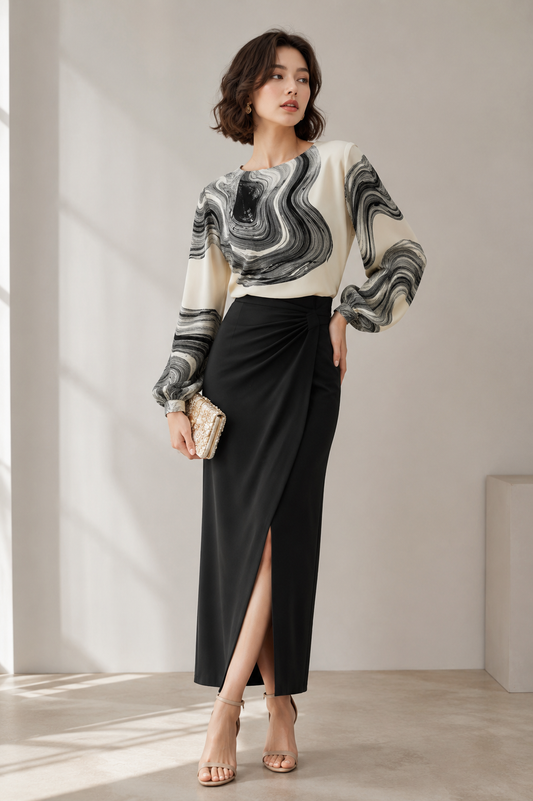 Woman wearing a black and ivory printed chiffon blouse with long sleeves and a round neckline.