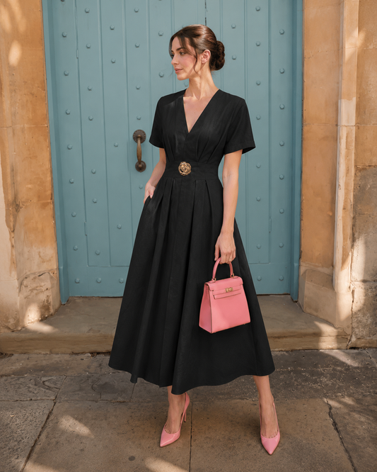 Woman wearing a black V-neck belted midi dress with a flowy skirt.