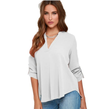 Woman wearing a blue V-neck roll sleeve blouse with rolled sleeves.