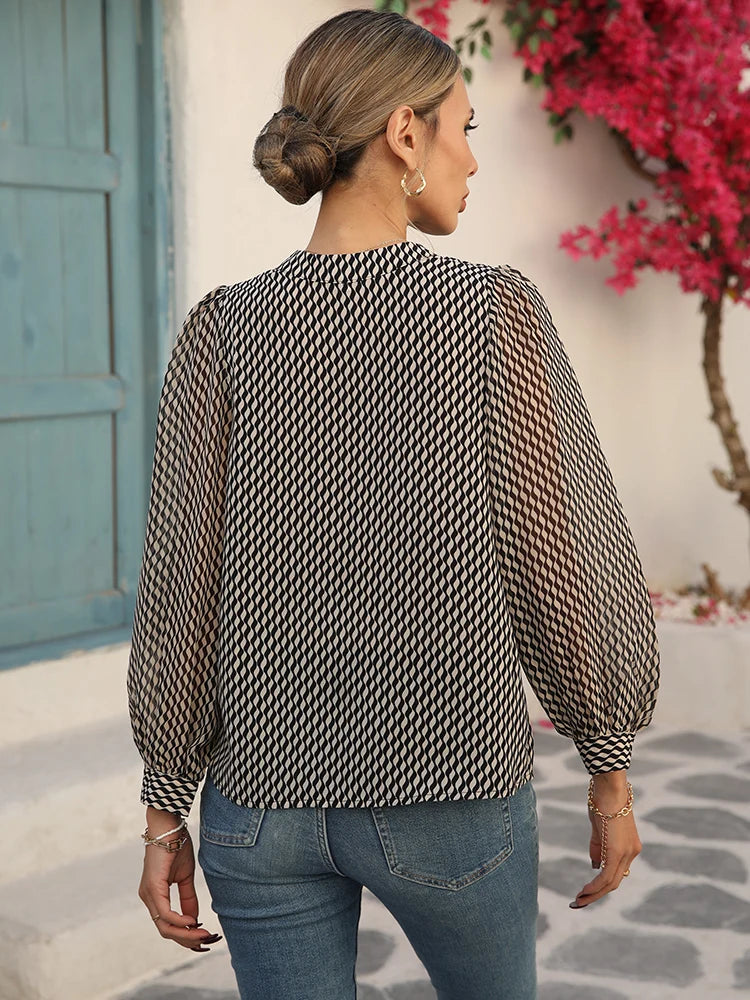Back view of a woman wearing a black and beige printed balloon sleeve blouse with a relaxed fit.