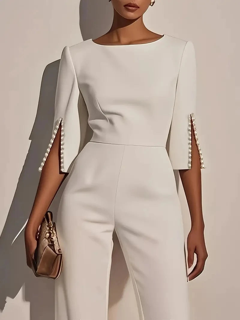 Woman wearing the Celina Studio Étoile Elegance Cape Sleeve Wide-Leg Jumpsuit in Pearl Ivory with pearl-trimmed cape sleeves.