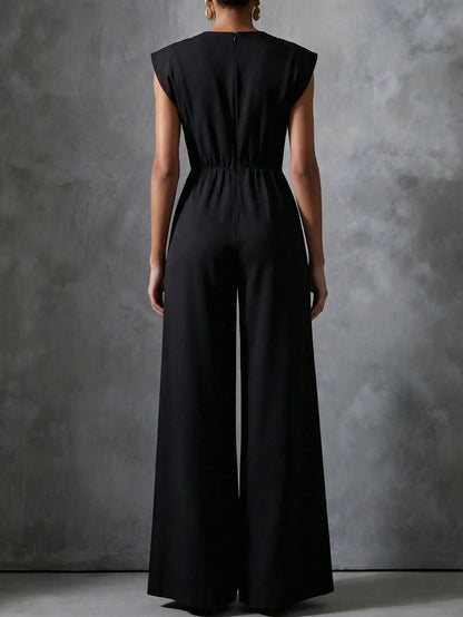 Woman wearing the Celina Studio Noir Luxe Tailored Wide-Leg Jumpsuit in Black with structured shoulders and flowing wide-leg trousers.