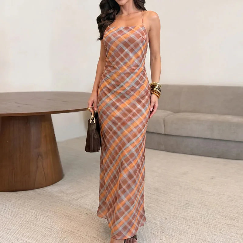Woman wearing an orange plaid cami maxi dress with spaghetti straps and a flowing silhouette.