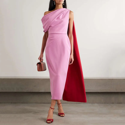 Woman wearing a pink one-shoulder cape midi dress with an elegant draped neckline.