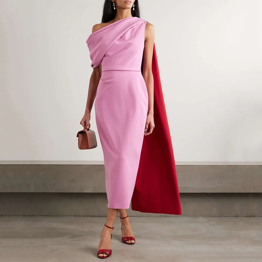 Woman wearing a pink one-shoulder cape midi dress with an elegant draped neckline.