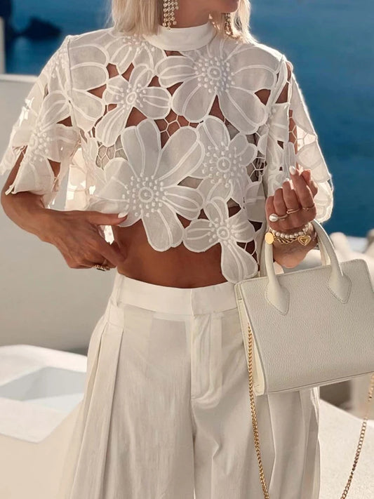 Woman wearing a white floral lace cutout blouse with a high neckline.