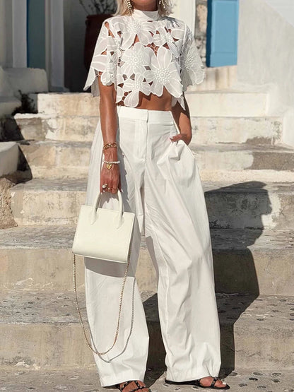 Woman styling a white floral lace blouse with white wide-leg pants.