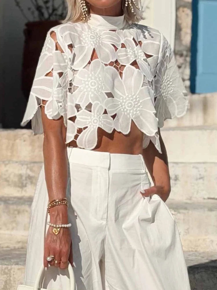 Side view of a white floral lace cutout blouse for women.