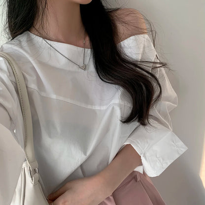 Close-up of a white elegant one-shoulder long sleeve blouse with an asymmetrical neckline.