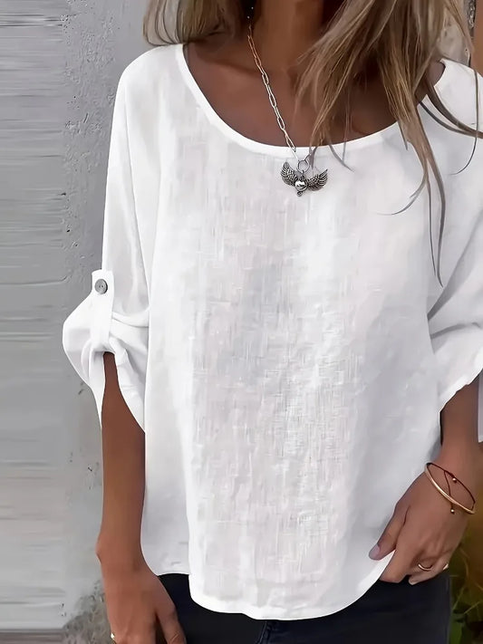 Woman wearing a white oversized linen blend blouse with rolled half sleeves.