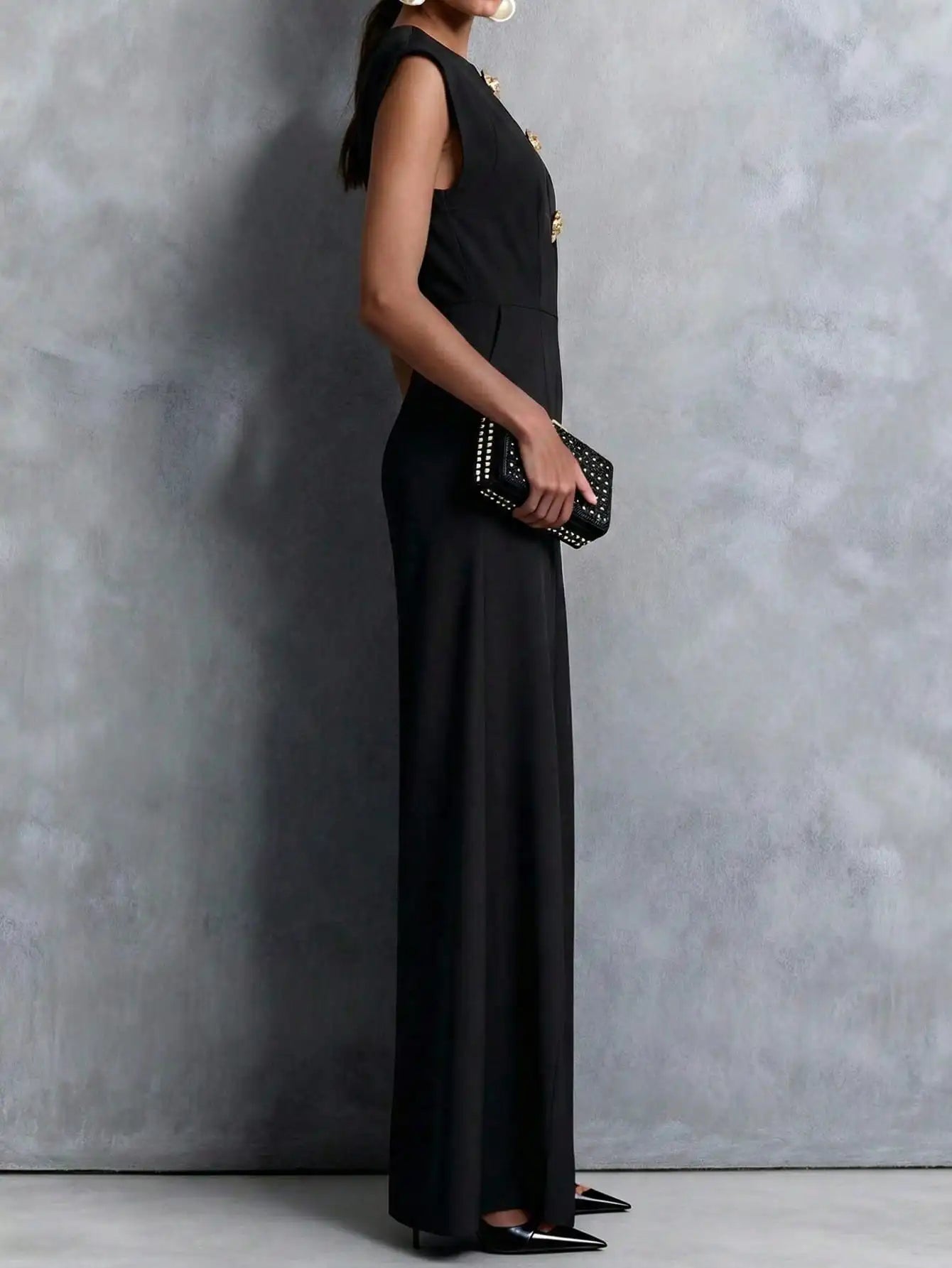 Woman wearing the Celina Studio Noir Luxe Tailored Wide-Leg Jumpsuit in Black with structured shoulders and flowing wide-leg trousers.