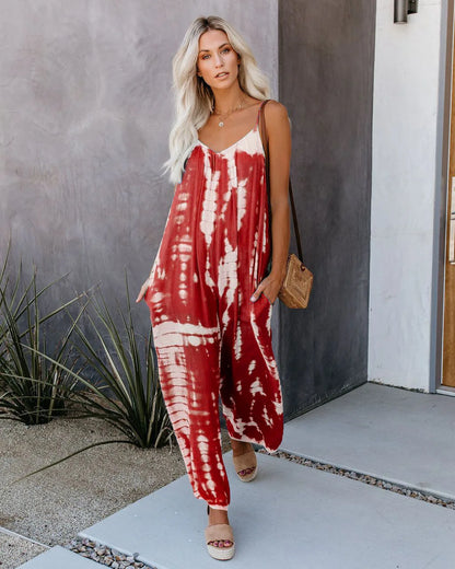 Woman wearing the Celina Studio Isla Breeze Printed Wide-Leg Jumpsuit in Coral Red with adjustable spaghetti straps and a relaxed wide-leg silhouette.