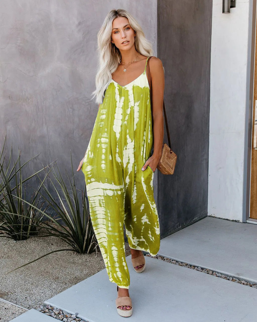 Woman wearing the Celina Studio Isla Breeze Printed Wide-Leg Jumpsuit in Lemon Lime with adjustable spaghetti straps and a relaxed wide-leg silhouette.